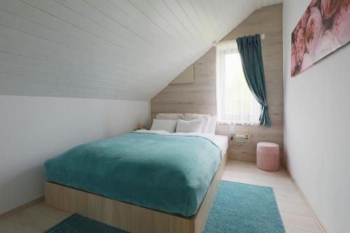 a bedroom with a bed with a blue blanket at Lotti Residnece Familyar in Balatonfüred