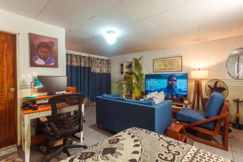 PALM Springs Bed & Breakfast في يمبي: غرفة نوم مع أريكة زرقاء ومكتب مع جهاز كمبيوتر