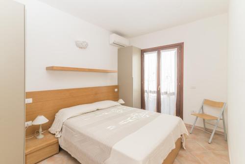 Habitación blanca con cama y ventana en Golfo Aranci - Gli Orizzonti 26, en Golfo Aranci