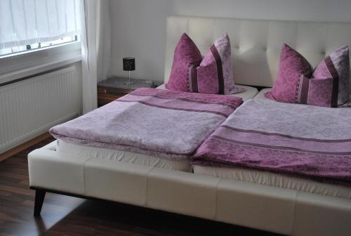 2 Betten in einem Zimmer mit lila Bettwäsche und Kissen in der Unterkunft FeWo Walburga in Roßbach