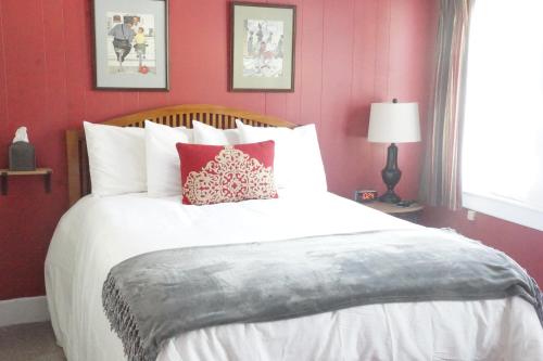 a bedroom with a large white bed with red walls at The Frogtown Inn in Canadensis
