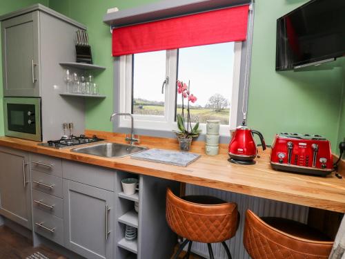 a kitchen with a counter with a sink and a window at Wild Acre in Llangadog