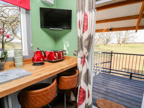 a room with a table and a television on a balcony at Wild Acre in Llangadog