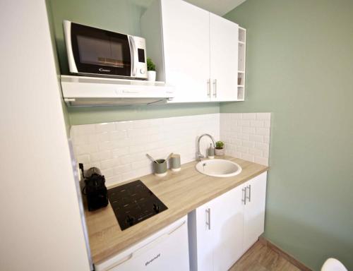 uma pequena cozinha com um lavatório e um micro-ondas em Studio Disneyland Paris em Montévrain