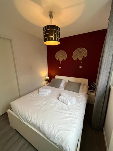 1 dormitorio con cama blanca y pared roja en Ceibo YourHostHelper, en Caen