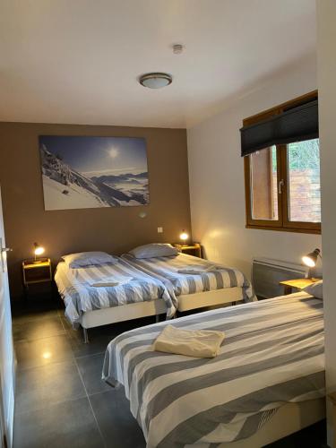 a bedroom with two beds and a tv on the wall at Le Chalet Carpe Diem in Le Bourg-dʼOisans