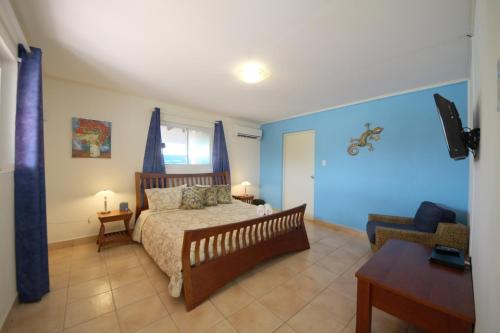 a bedroom with blue walls and a bed and a table at Agave Gardens in Palm-Eagle Beach