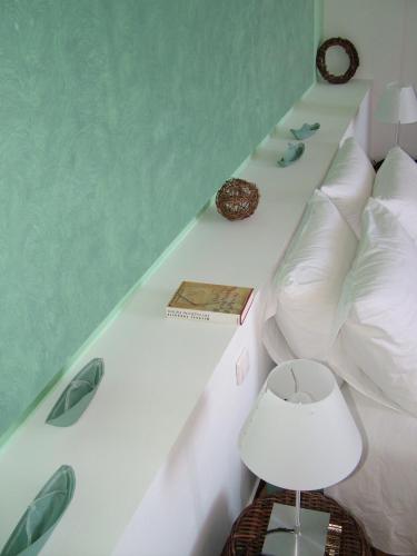 a bedroom with a white bed with a green wall at Manos Small World in Firostefani