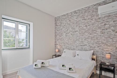 a white bedroom with a brick wall and a bed at BmyGuest - Cascais Beach Villa I in Cascais