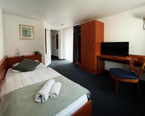 a hotel room with a bed with a desk and a tv at Hotel am Malerwinkel in Wertheim