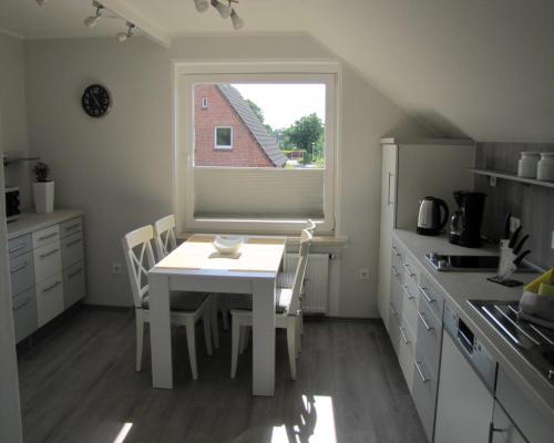 a kitchen with a white table and a window at FeWo-Möwenpaar-Norden-Norddeich in Norden