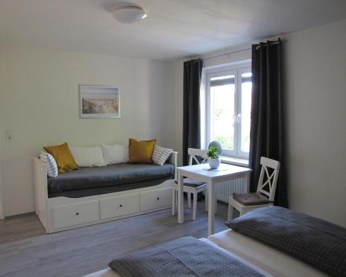 ein Schlafzimmer mit einem Sofa, einem Tisch und einem Fenster in der Unterkunft FeWo-Möwenpaar-Norden-Norddeich in Norden
