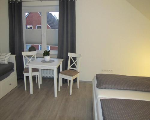 a bedroom with a table and chairs and a bed at FeWo-Möwenpaar-Norden-Norddeich in Norden