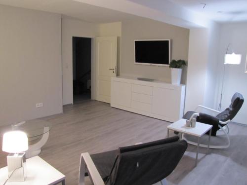 a living room with chairs and a tv on a wall at FeWo-Möwenpaar-Norden-Norddeich in Norden