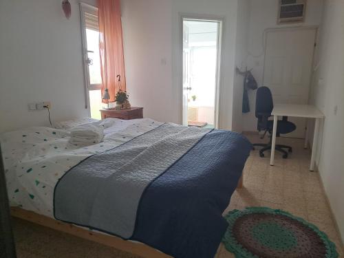 a bedroom with a bed with a blue blanket on it at Galilean villa with jacuzzi in Qiryat ‘Amal