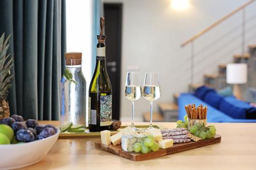 a table with two wine glasses and a plate of cheese and grapes at Moft Loft. Lovely, comfy apartment. in Cluj-Napoca