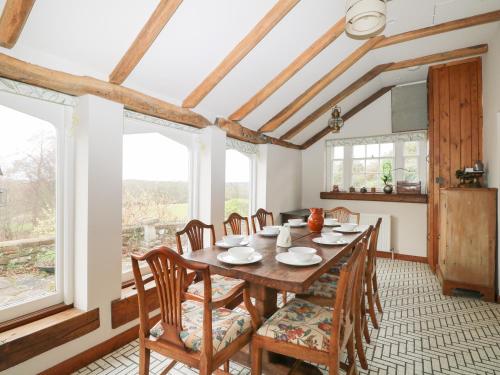 a dining room with a table and chairs and windows at Paythorne Farmhouse in Henfield