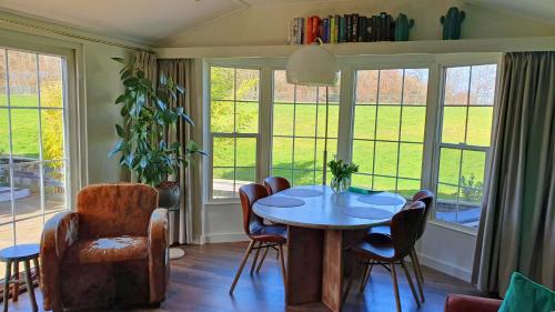 uma sala de jantar com mesa, cadeiras e janelas em dutchduochalet2 em Heenweg