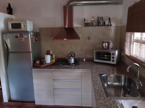 cocina con nevera, fregadero y microondas en Un Lugar Encantador - Chalet con Hermoso Parque, Pileta y Solárium en Open Door