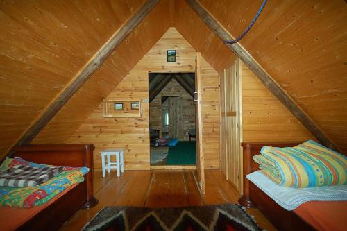 a room with two beds in a wooden cabin at Chata Trapera na Groniu in Koszarawa