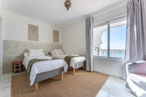 a white bedroom with two beds and a window at Oasis la Cala in Mijas