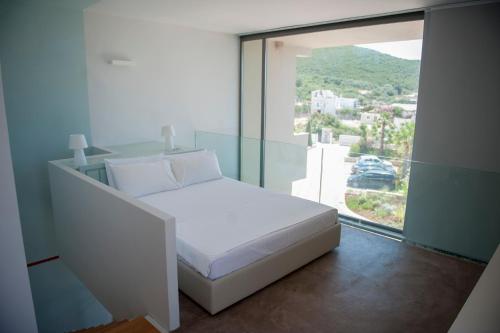 a white bed in a room with a large window at Soleil Village & Villas in Jal