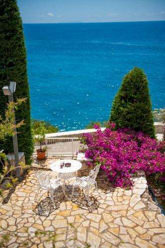 a patio with a table and purple flowers and the ocean at Soleil Village & Villas in Jal