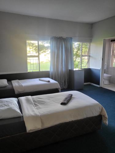 a hotel room with two beds and a window at Legends Lodge in Ermelo