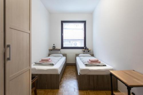 twee bedden in een kleine kamer met een raam bij BIG PIPE apartment in Ljubljana