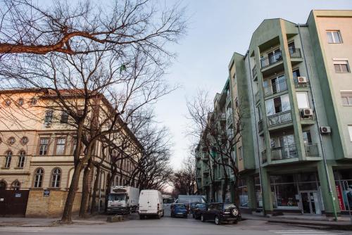 a city street with cars parked next to buildings at ĐILL 2 APARTMANTS in Subotica