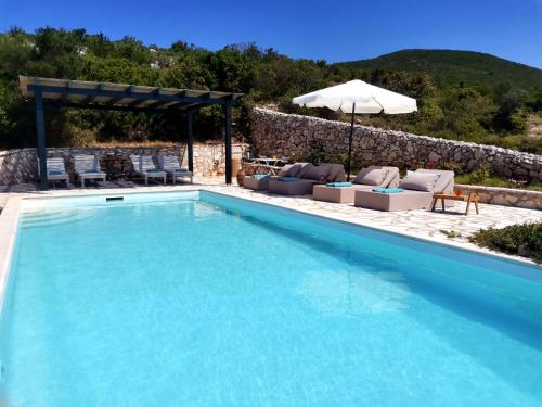 a swimming pool with chairs and an umbrella at Urania Luxury Villa Geofos in Póndi