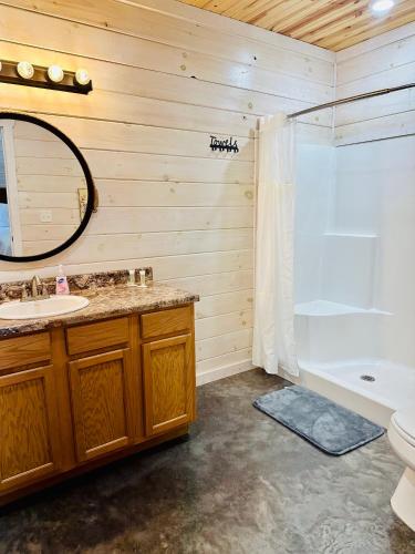a bathroom with a sink and a tub and a mirror at Knotty Squirrel Cabins in Mountain View