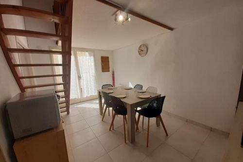 a dining room with a table and chairs and a clock at Small villa 40m with terrace near the beach in Fleury