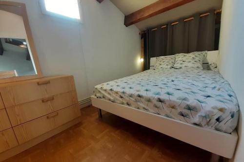 a bedroom with a bed and a dresser and a mirror at Small villa 40m with terrace near the beach in Fleury