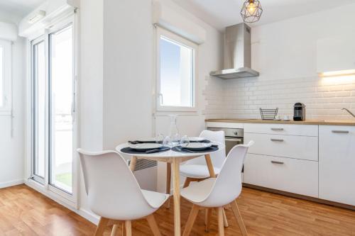 biała kuchnia ze stołem i białymi krzesłami w obiekcie Cosy 40m with terrace in Vannes w mieście Vannes