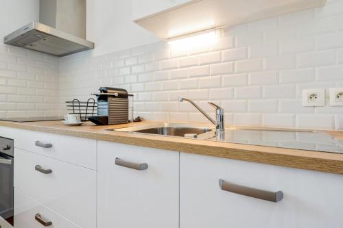 - une cuisine avec des placards blancs et un évier dans l'établissement Cosy 40m with terrace in Vannes, à Vannes