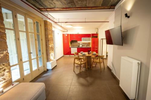 Zimmer mit einem Tisch und einer Küche mit roten Schränken in der Unterkunft Filopapou Pearl on Acropolis Hill in Athen
