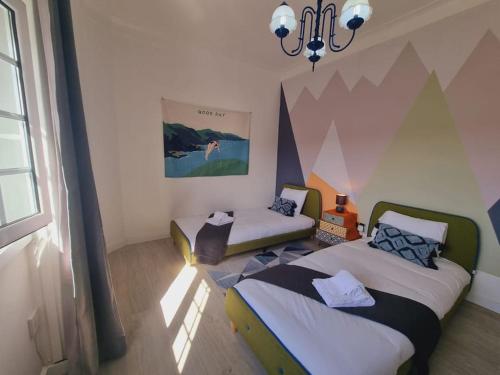 1 dormitorio con 2 camas y lámpara de araña en Almada central by Innkeeper, en Almada