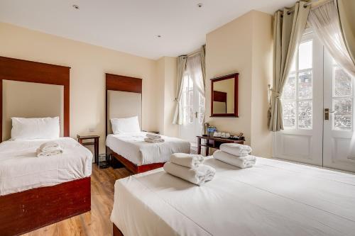 a bedroom with two beds with white sheets at Astoria Hotel in London