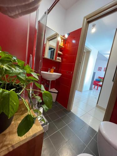 a bathroom with red walls and a toilet and a sink at Genova La casa di Saretta in Marina di Ragusa