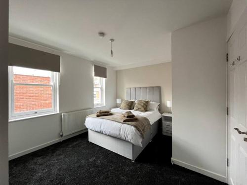 a white bedroom with a bed and a window at Ivory House, central modern town house in Leamington Spa
