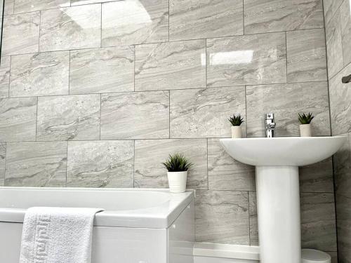 a bathroom with a sink and a tub and a toilet at Ivory House, central modern town house in Leamington Spa