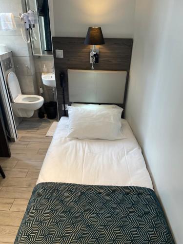 ein kleines Schlafzimmer mit einem Bett und einem WC in der Unterkunft Mary's Hotel République in Paris