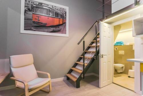 un escalier dans une pièce avec une chaise et un tableau de train dans l'établissement Apartments Síp, à Budapest
