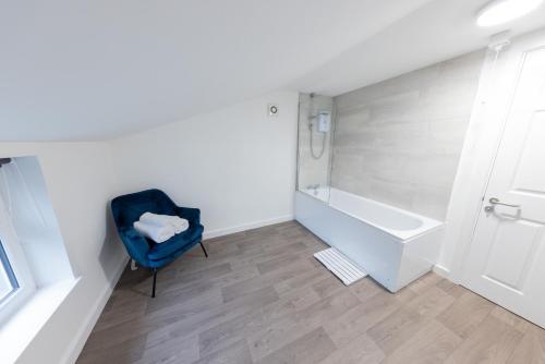 a bathroom with a blue chair and a bath tub at Havana House in Wolverhampton