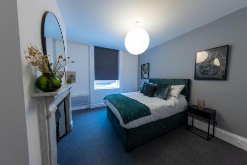 Dormitorio azul con cama y espejo en Havana House, en Wolverhampton
