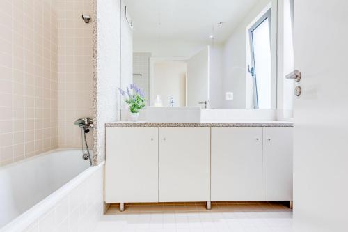 ein weißes Badezimmer mit einem Waschbecken und einer Badewanne in der Unterkunft Casa do Poço in Caminha