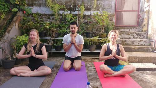 un grupo de tres personas sentadas en una pose de yoga en Chacha Homestay & Dormitory en Ruteng