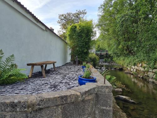 a stone wall with a bench next to a river at Cosy Riverside home in Llanwrda