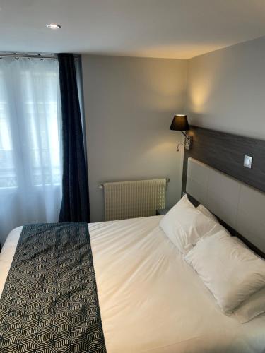 a bed in a hotel room with a white bedspread at Mary's Hotel République in Paris